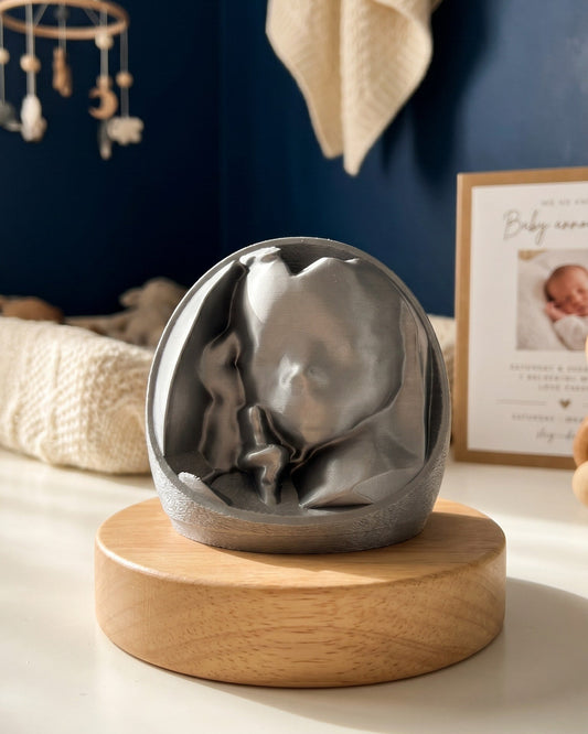 A 3D printed ultrasound keepsake, displayed on a round light wood base on a white tabletop.
