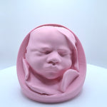 A light pink 3D printed replica of a sleeping newborn baby's head in a belly.