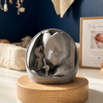 A 3D printed ultrasound keepsake, displayed on a round light wood base on a white tabletop.